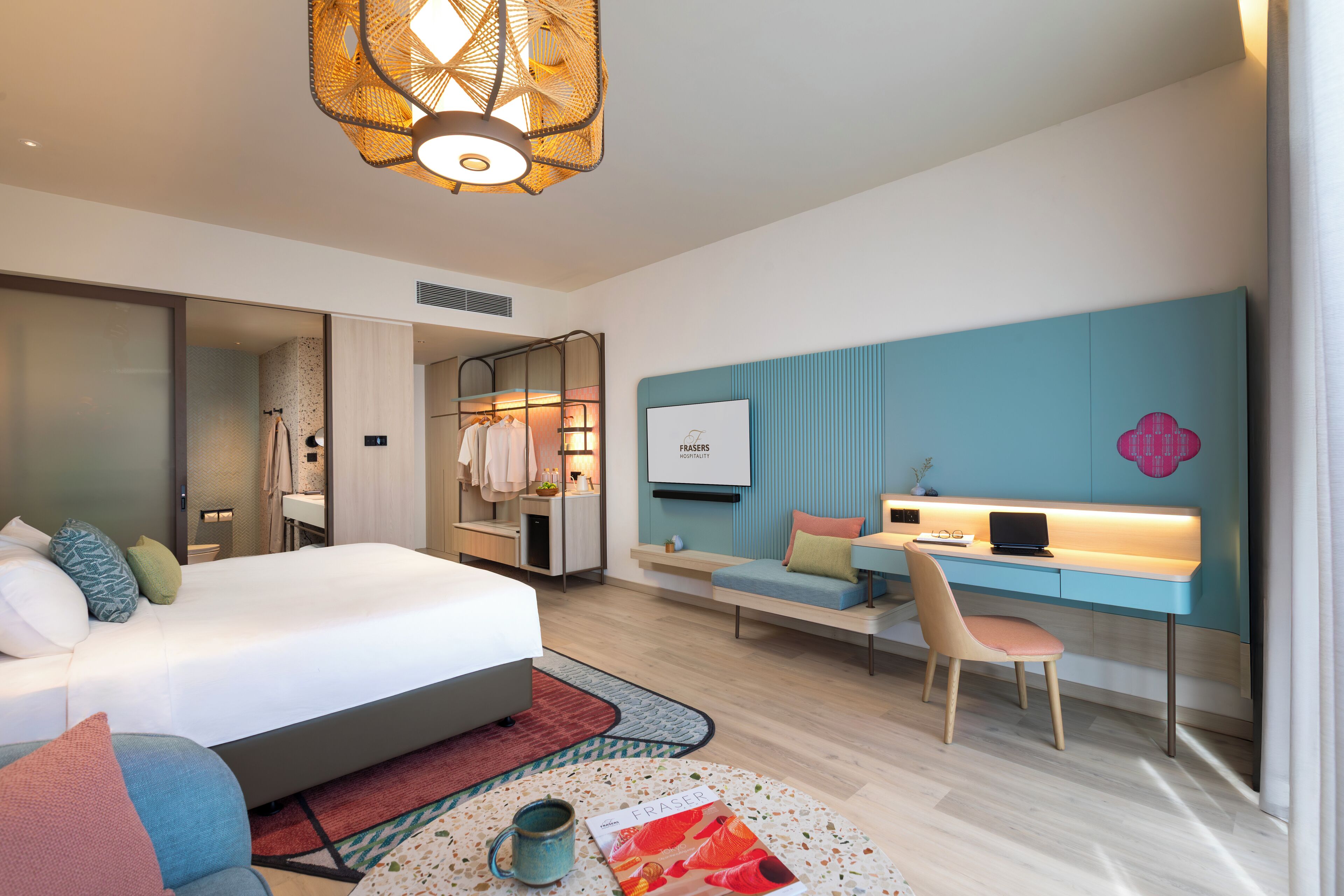 Habitación de hotel moderna con una cama grande, un escritorio con una computadora portátil, una zona de estar y un televisor en la pared.