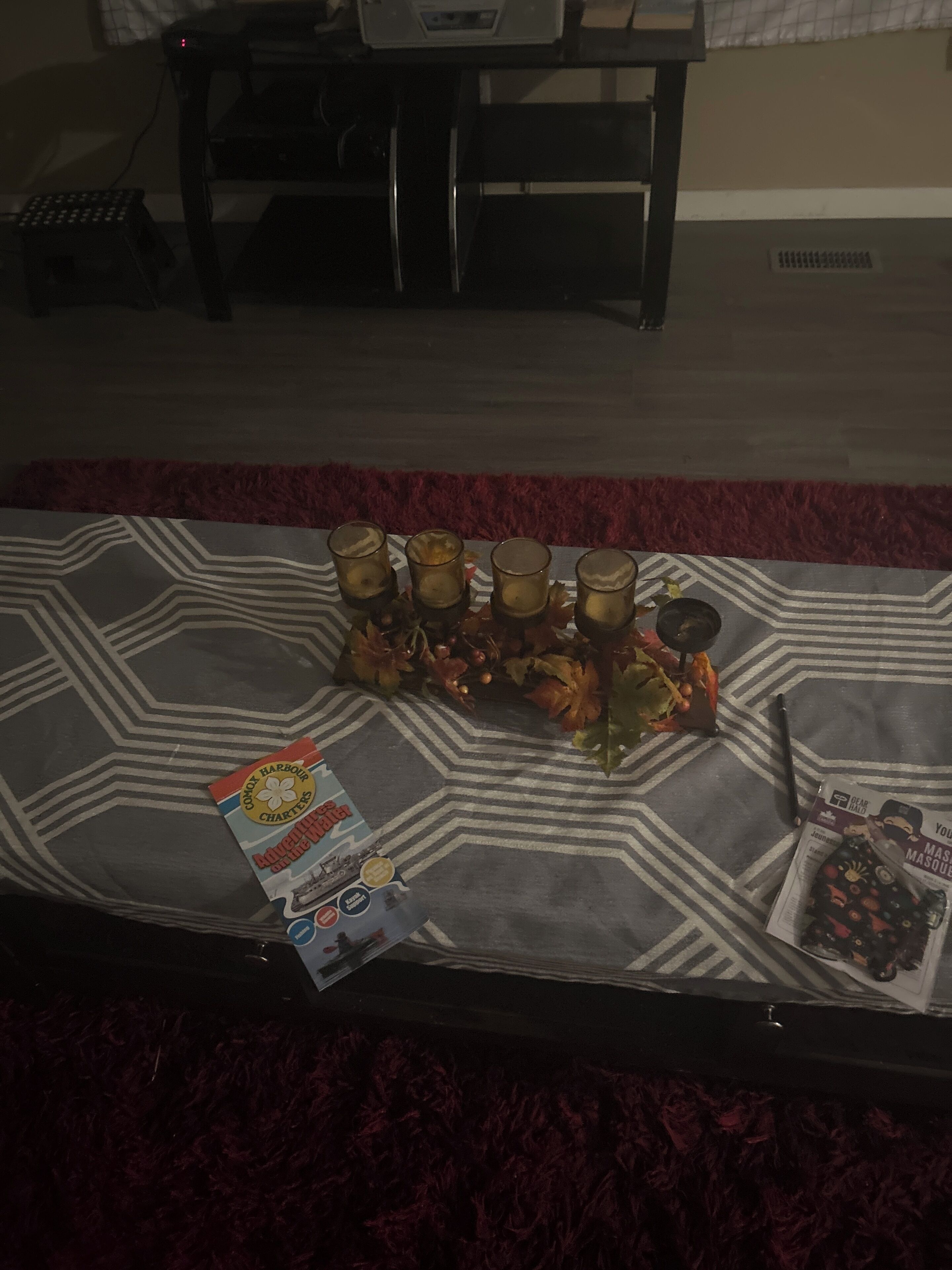 A table with a patterned tablecloth, a card, and a magazine on it.