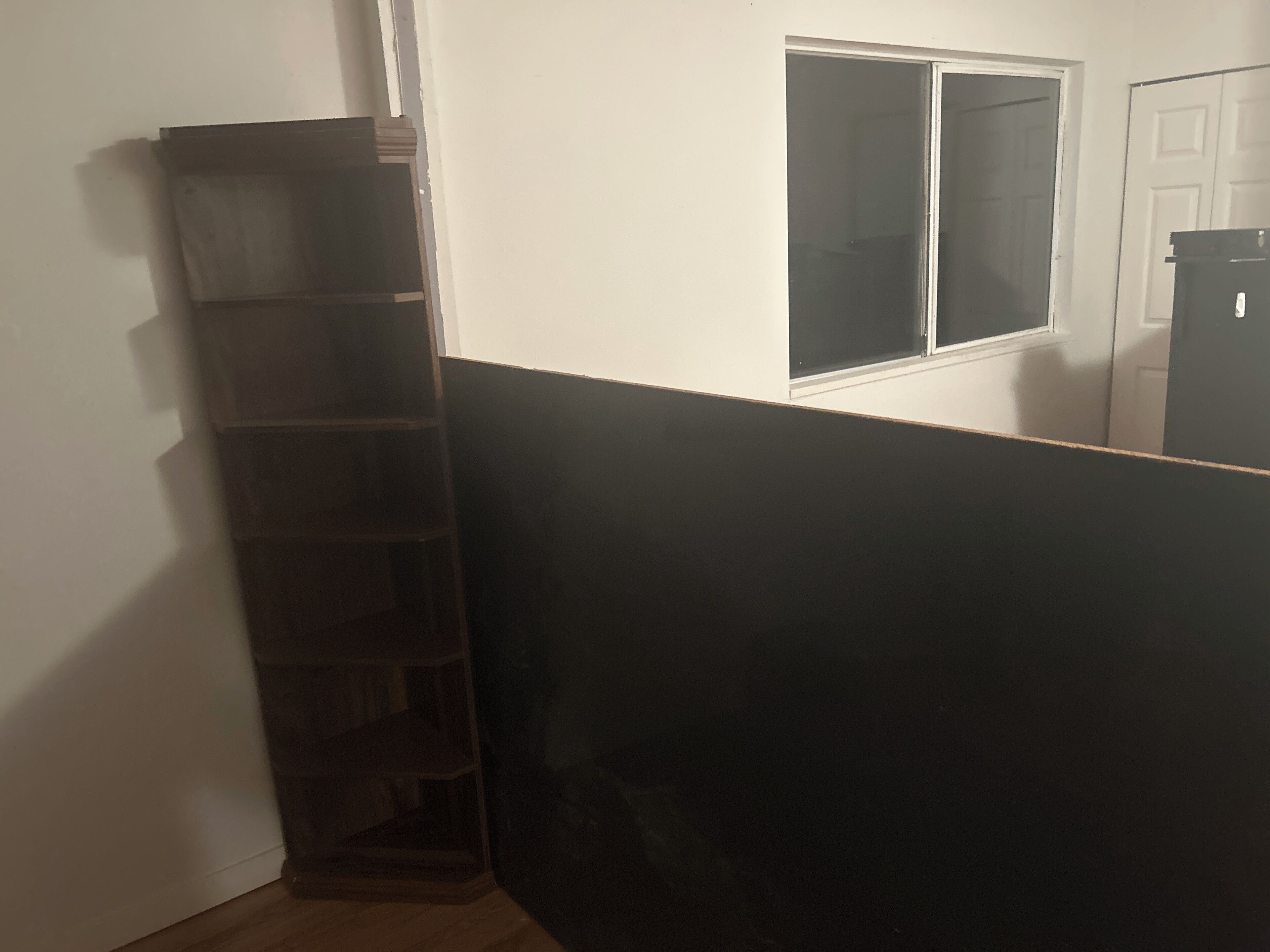 Ein Zimmer mit Holzboden, weißer Wand, Fenster und Tür.
