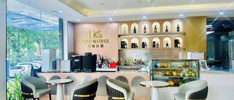 Una cafetería moderna con mostrador, zona de estar y exhibición de bebidas.
