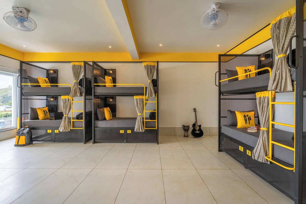 Ein Zimmer mit Etagenbetten, einer Gitarre und einem Ventilator.