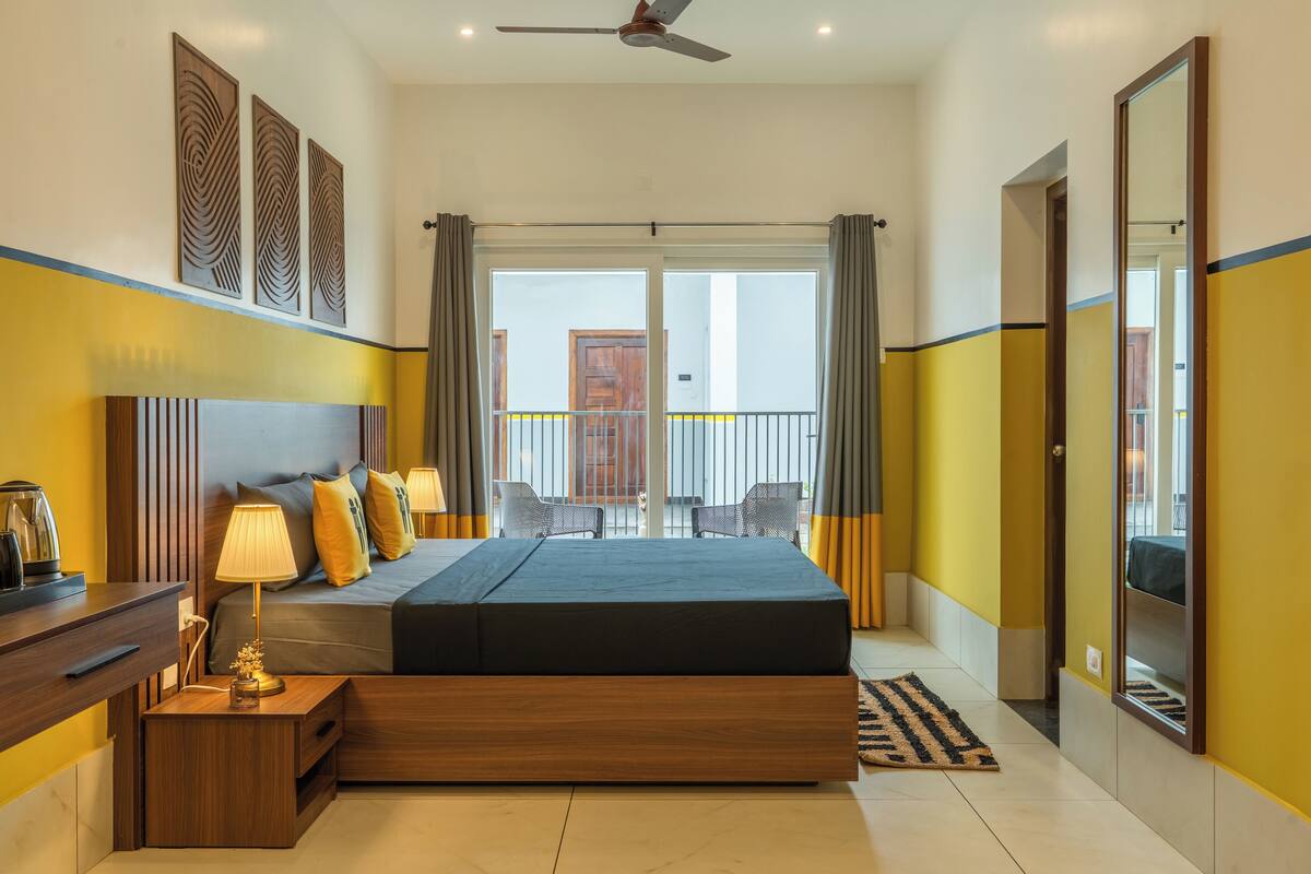 Ein Hotelzimmer mit einem großen Bett, Nachttischen, einem Deckenventilator und einem Balkon mit Stühlen.