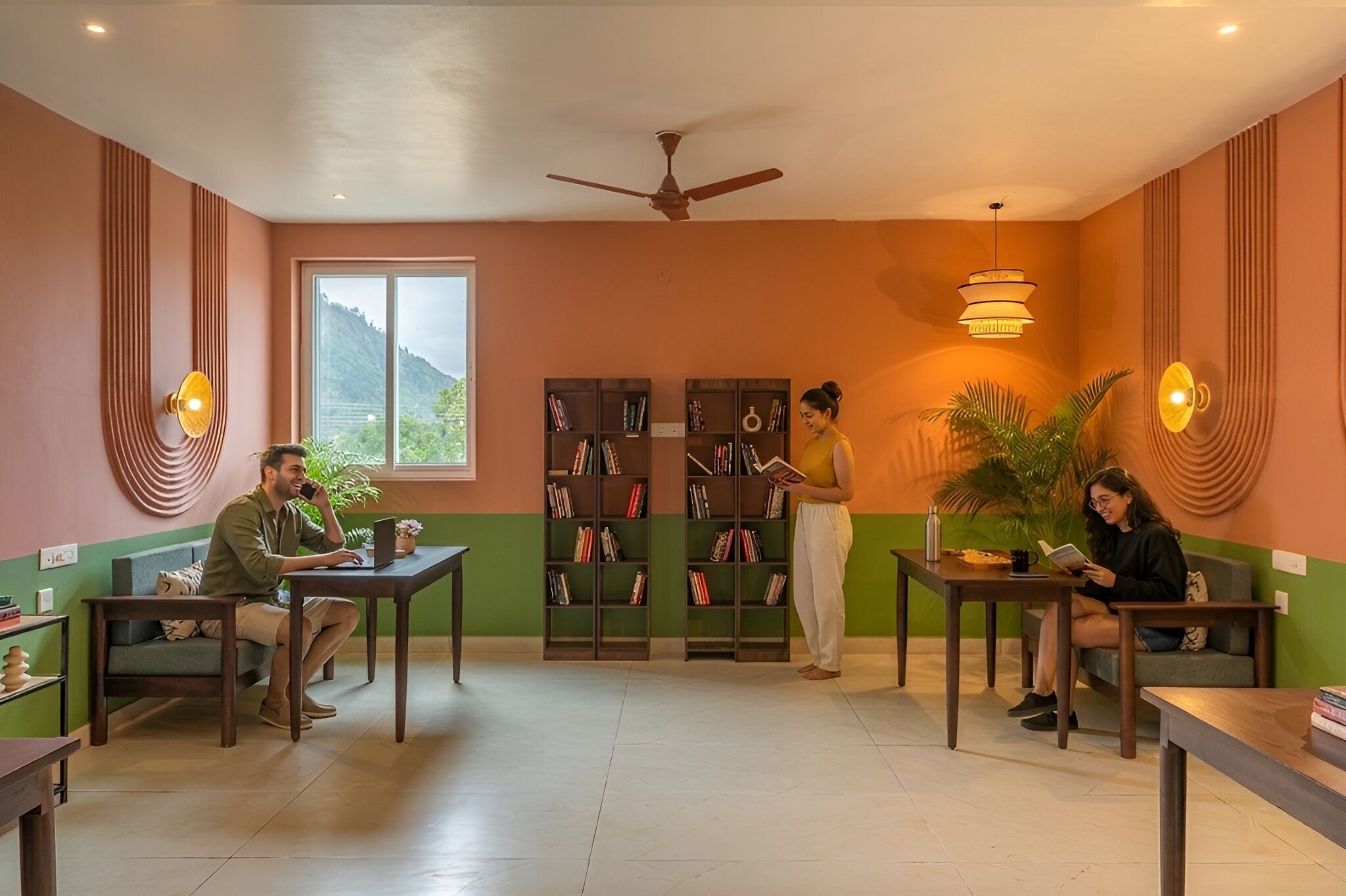 Una habitación con ventilador de techo, estanterías, una ventana con vistas y una pared verde.