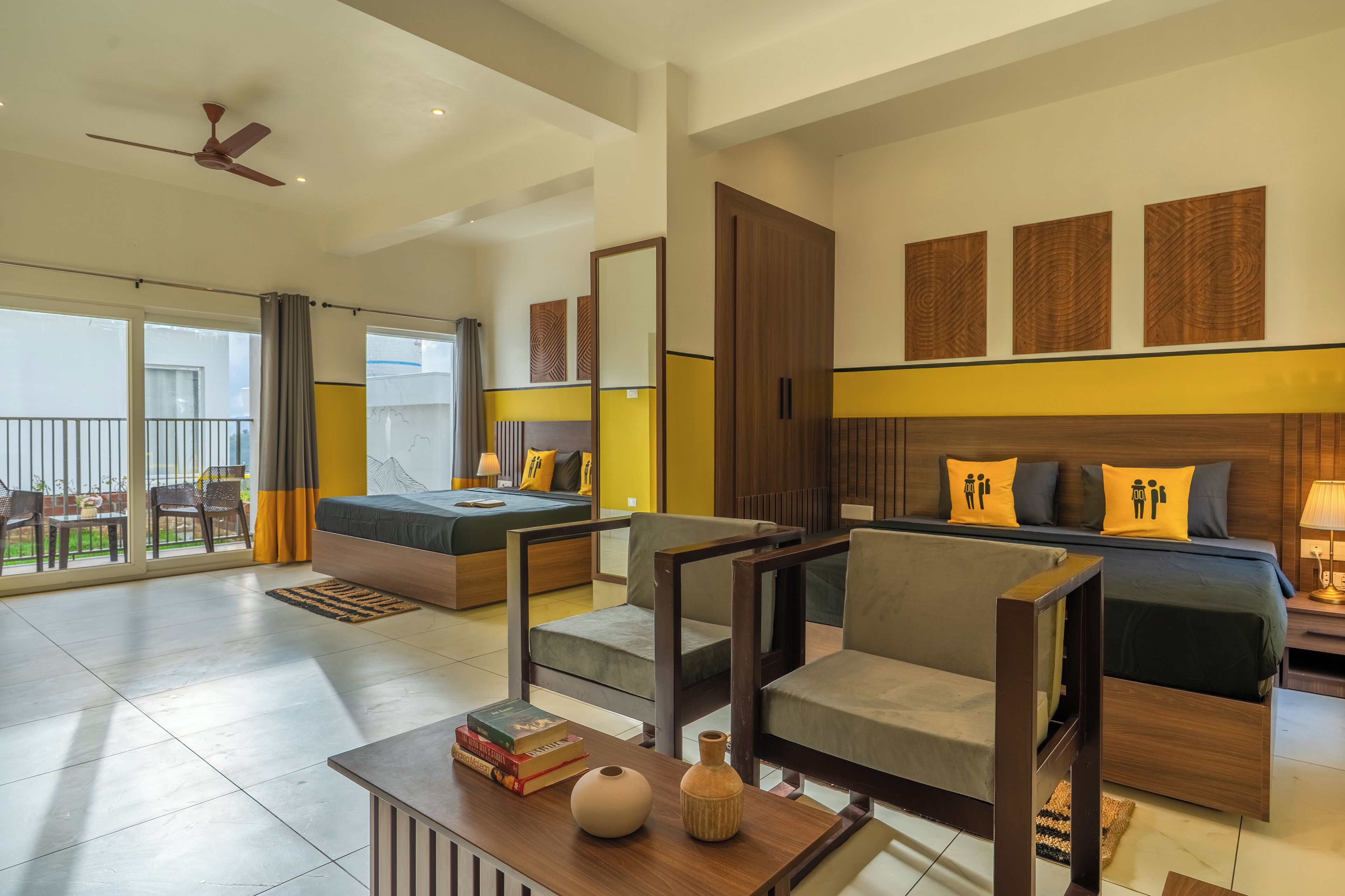 A modern hotel room with a balcony, a sofa bed, a wooden coffee table, and a TV.