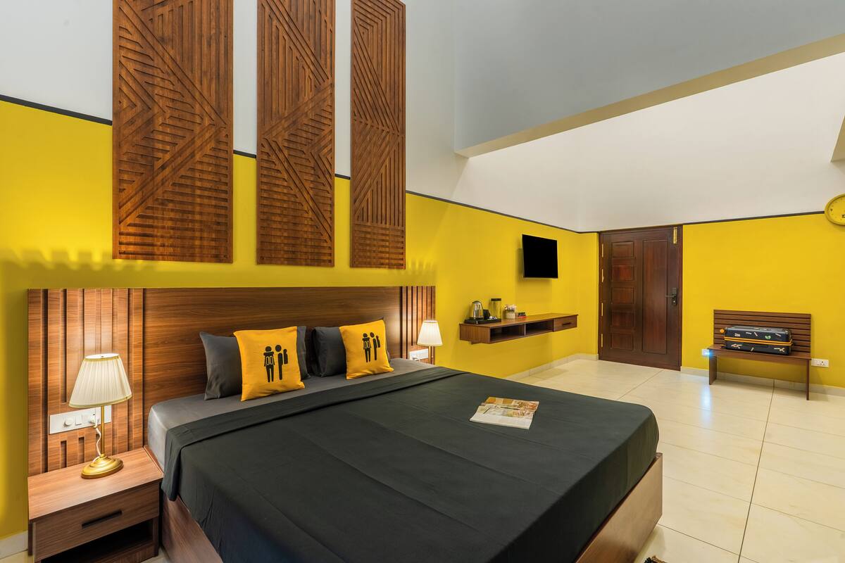Ein Schlafzimmer mit Bett, Nachttisch, Lampe und Sitzbank.