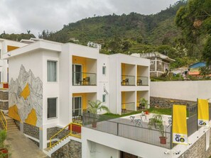 Ein mehrgeschossiges Gebäude mit Balkonen, einer Treppe und einem Wandbild von Bergen.