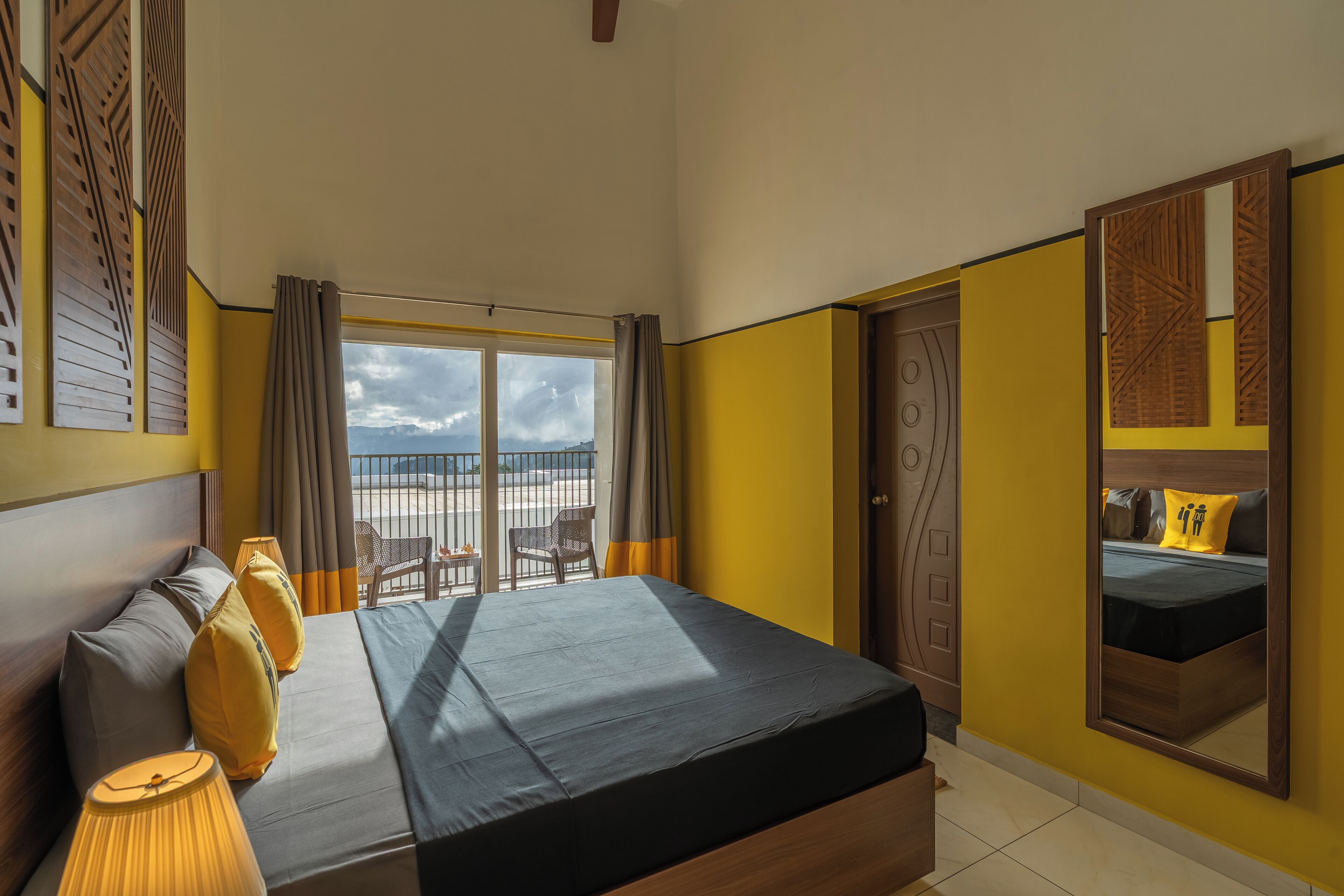 A hotel room with a bed, a view of the beach, and a balcony with chairs.