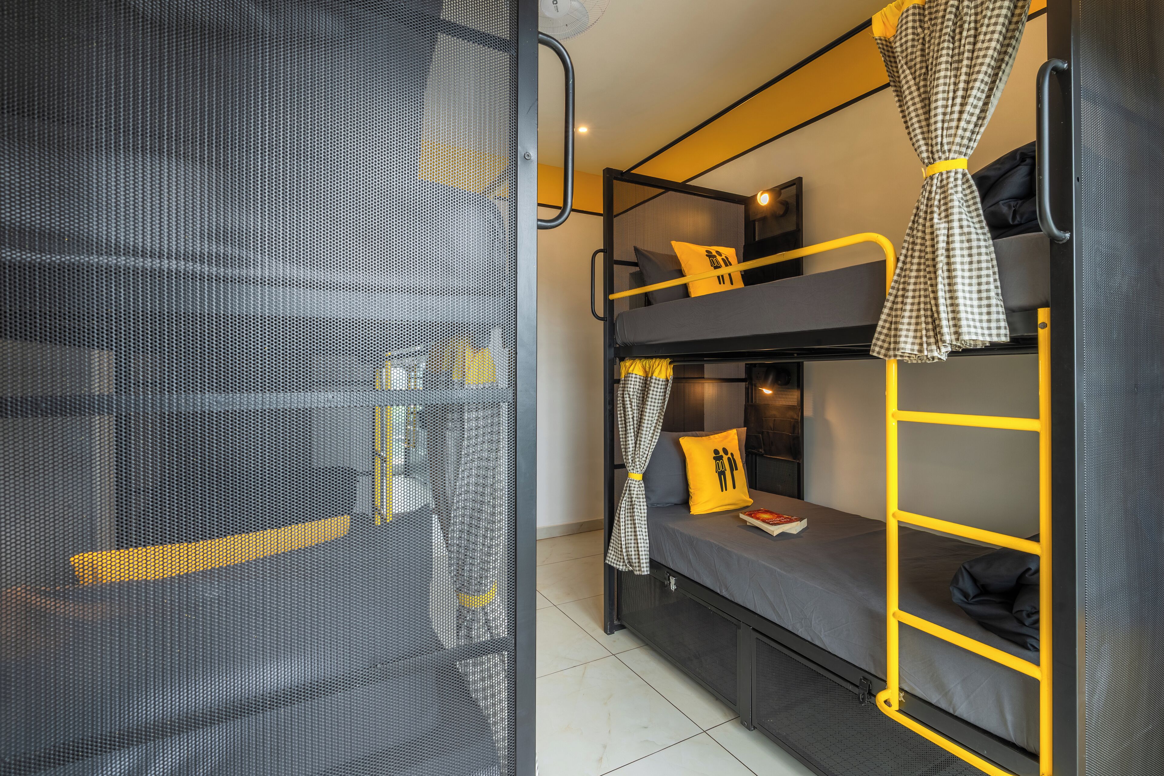 A bunk bed room with a mesh screen door, a small table, and a bed with a yellow pillow.