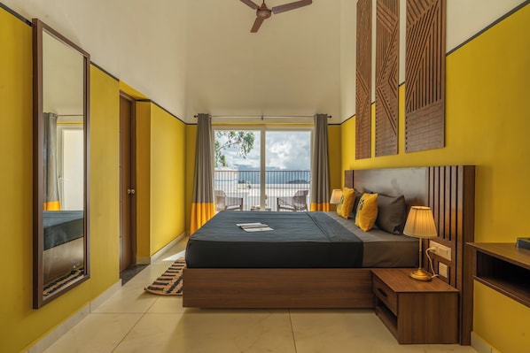 A bedroom with a bed, bedside table, and a view of the outdoors.