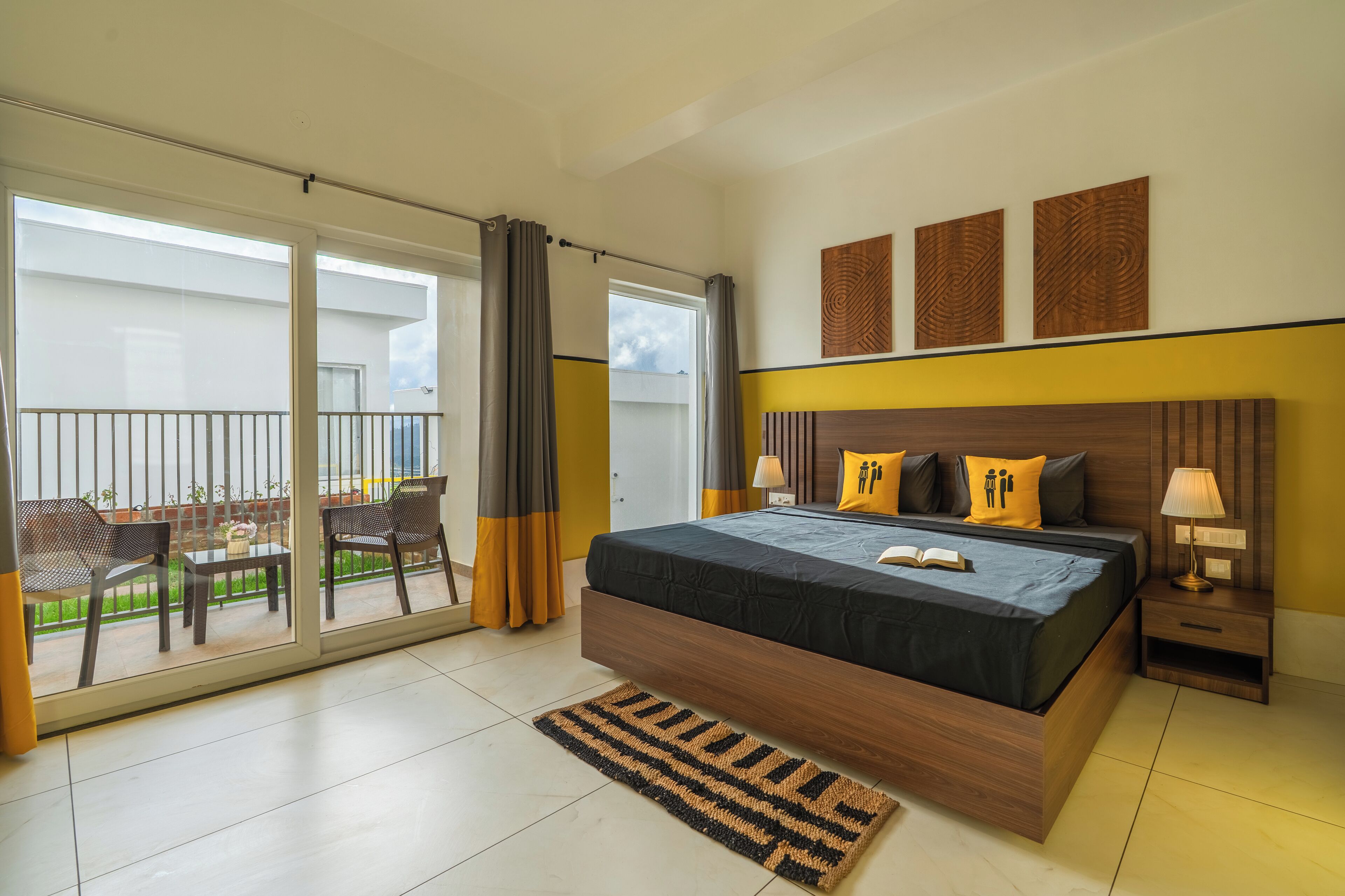 Un dormitorio con una cama grande, una mesita de noche, una mesa con sillas y vistas al balcón exterior.