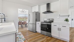 Una cucina moderna con mobili bianchi, elettrodomestici in acciaio inossidabile e pavimento in legno.