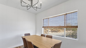Una sala conferenze con un tavolo in legno e sedie marroni, ampie finestre con tende e un lampadario moderno.