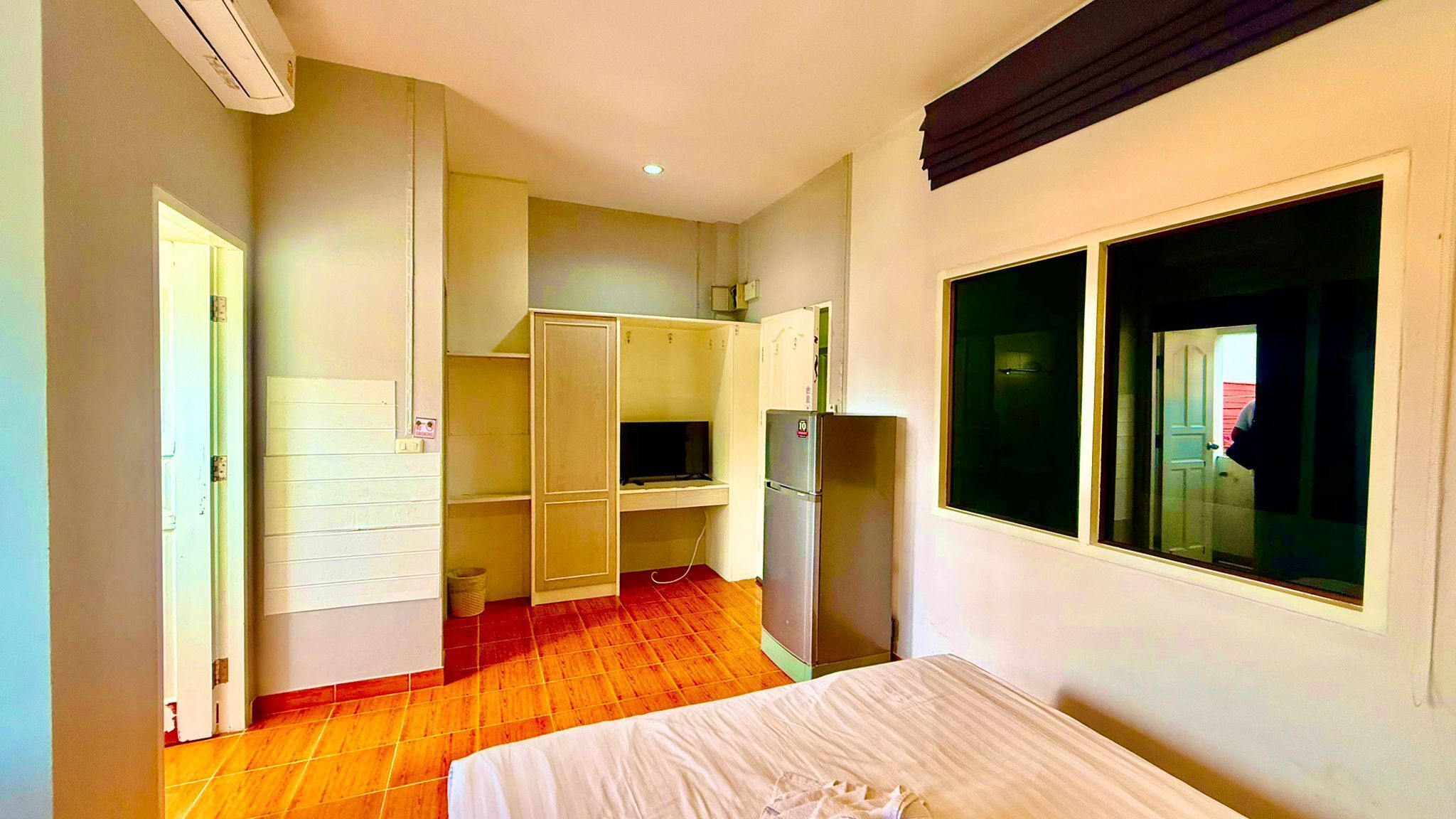 A compact room with a bed, a built-in wardrobe, a small kitchenette, and a window with a view.
