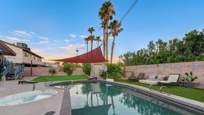 A swimming pool with lounge chairs, a red shade sail, and palm trees in the background. - Strip-Side Villa, 6 Beds, Pool, Mini Golf, Karaoke (Las Vegas)