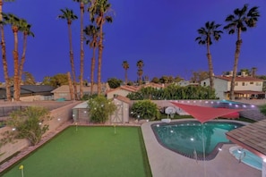 A pool area with a green lawn, palm trees, and a red canopy. - Strip-Side Villa, 6 Beds, Pool, Mini Golf, Karaoke (Las Vegas)