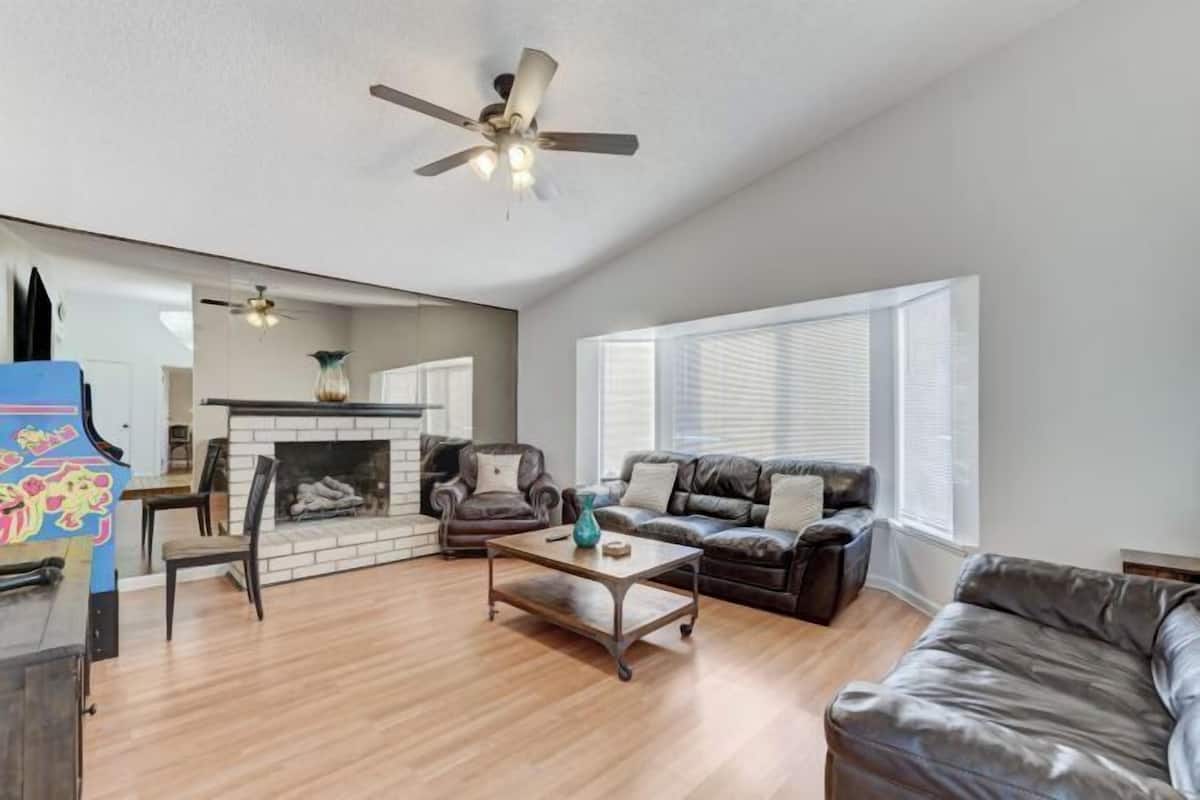 A living room with a fireplace, leather sofas, a coffee table, and a ceiling fan.