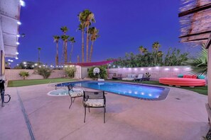 A swimming pool with lounge chairs and a basketball hoop, surrounded by palm trees and string lights. - Strip-Side Villa, 6 Beds, Pool, Mini Golf, Karaoke (Las Vegas)