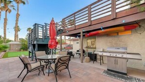 An outdoor patio with a grill, seating area, and a red umbrella. - Strip-Side Villa, 6 Beds, Pool, Mini Golf, Karaoke (Las Vegas)