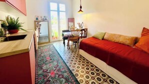 Una cucina compatta con zona pranzo, un divano rosso e un tappeto decorato.