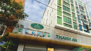 Um hotel chamado Thanh An, com fachada moderna, entrada visível e um carro vermelho estacionado na frente.