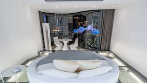 Une chambre d’hôtel moderne avec un grand lit, une petite table et un coin salon avec des fauteuils.