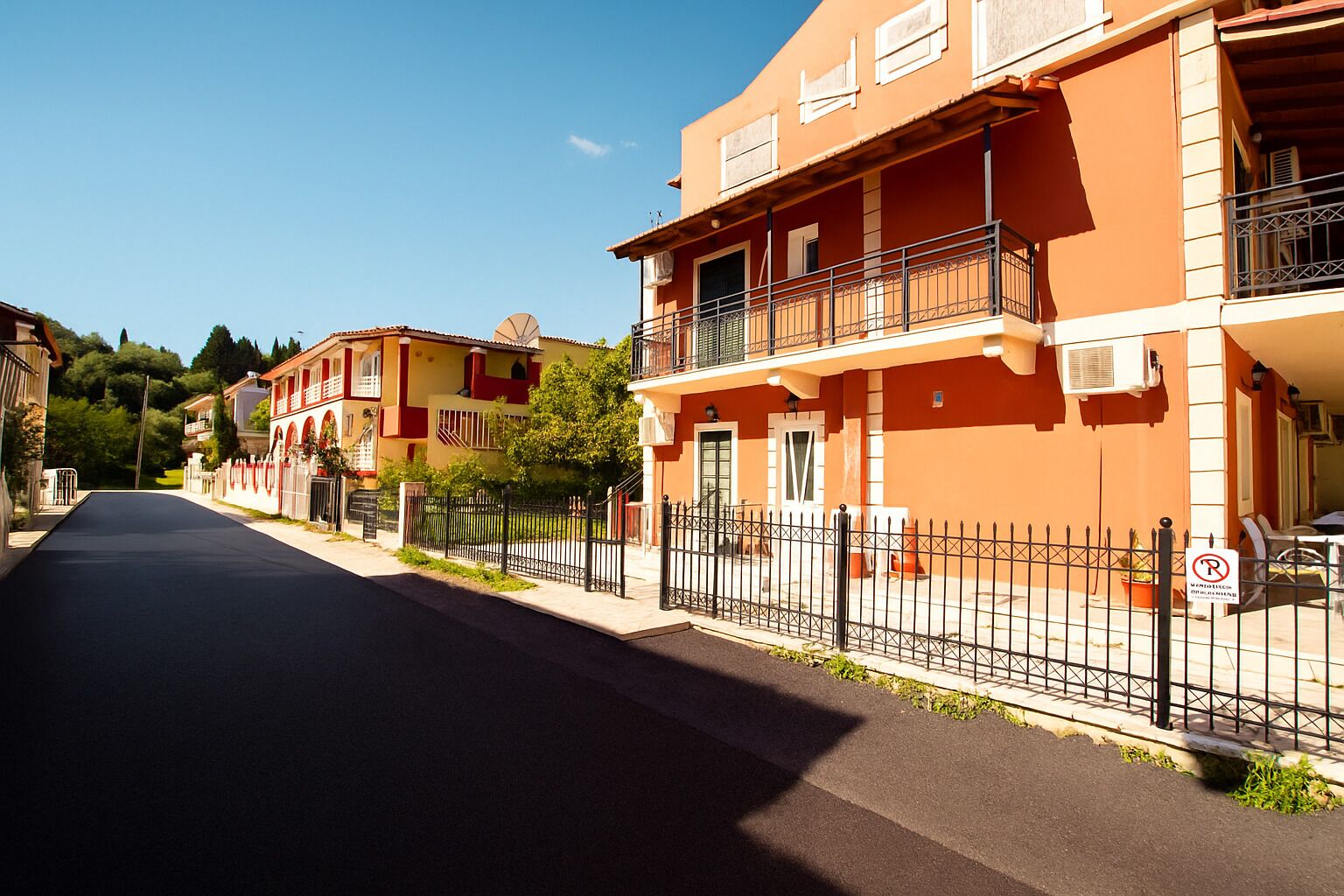 A street with a row of orange buildings, each with balconies and air conditioning units.