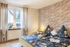 Una camera da letto con un letto, tende, un comodino, una lampada e una finestra vista.