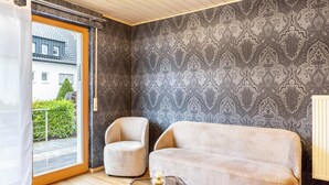 A room with a sofa, armchair, and a glass table with a candle. - Apartment 'Marisa's Sauerland Dream' with Shared Terrace, Garden & Wi-Fi (Brilon)
