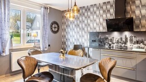 A modern kitchen with a dining table, chairs, and a cityscape artwork on the wall. - Apartment 'Marisa's Sauerland Dream' with Shared Terrace, Garden & Wi-Fi (Brilon)