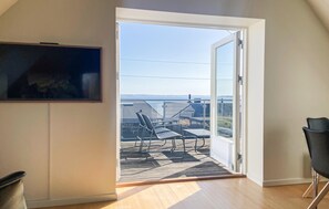 Een open deur die leidt naar een balkon met uitzicht, een stoel en een tafel.