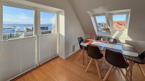 A modern dining area with a view of the sea, large windows, and a sloped ceiling. - Awesome home in Egernsund with house sea view (Egernsund)