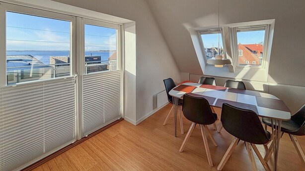 Ett modernt matområde med utsikt över havet, stora fönster och ett sluttande tak.