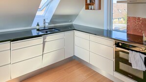 A modern kitchen with white cabinets, a black countertop, a built-in oven, and a skylight. - Awesome home in Egernsund with house sea view (Egernsund)