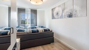 Ein modernes Schlafzimmer mit einem Bett, einem Fenster und einem an der Wand befestigten Kunstwerk.