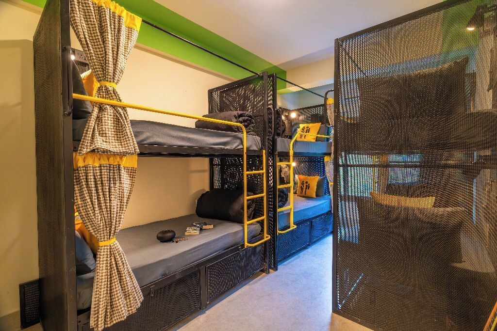 A bunk bed room with a ladder, a small table, and a blue sofa.