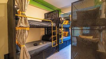 A bunk bed room with a ladder, a small table, and a blue sofa.
