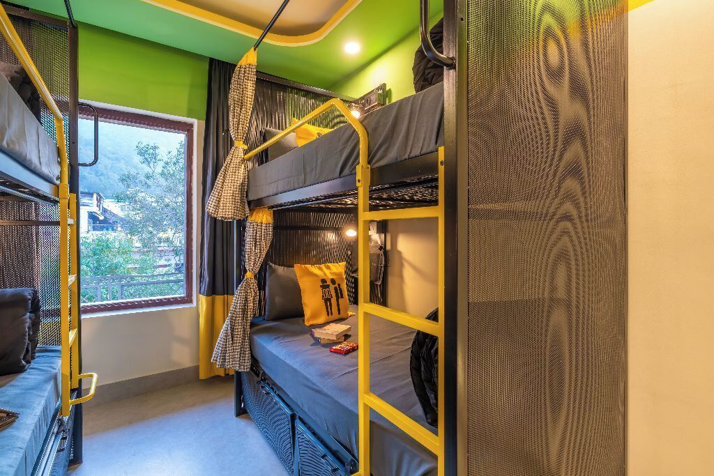 A compact room with bunk beds, a window with curtains, and a small desk area.
