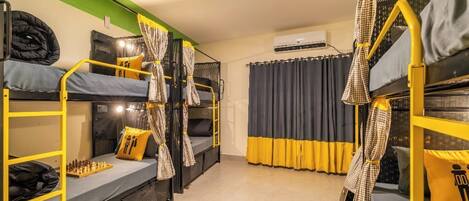A dormitory room with bunk beds, a chessboard, and curtains.