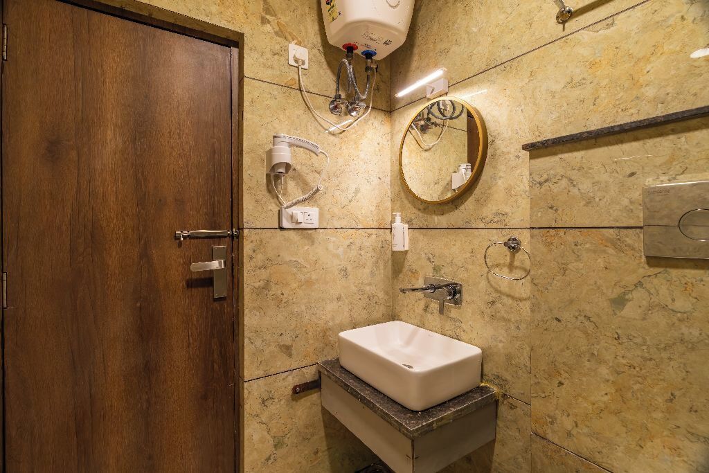 Ein Badezimmer mit Holztür, Marmorwand, Waschbecken, Spiegel und Handtuchhalter.