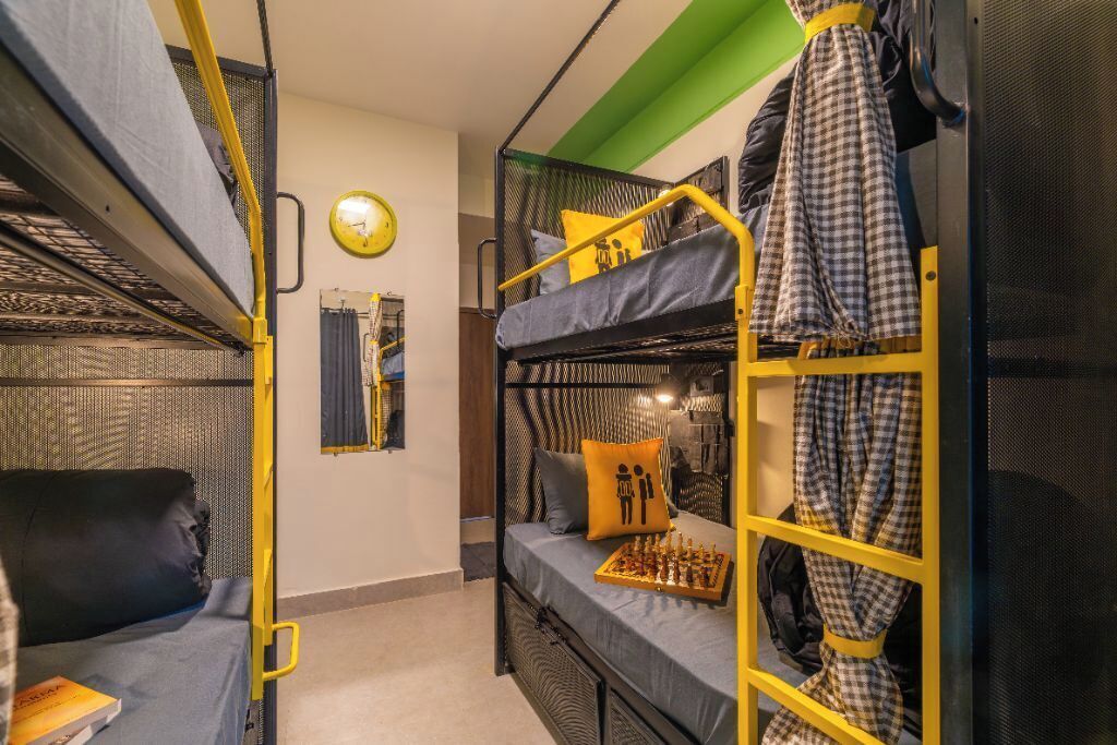 A compact room with bunk beds, a chessboard, and a clock on the wall.