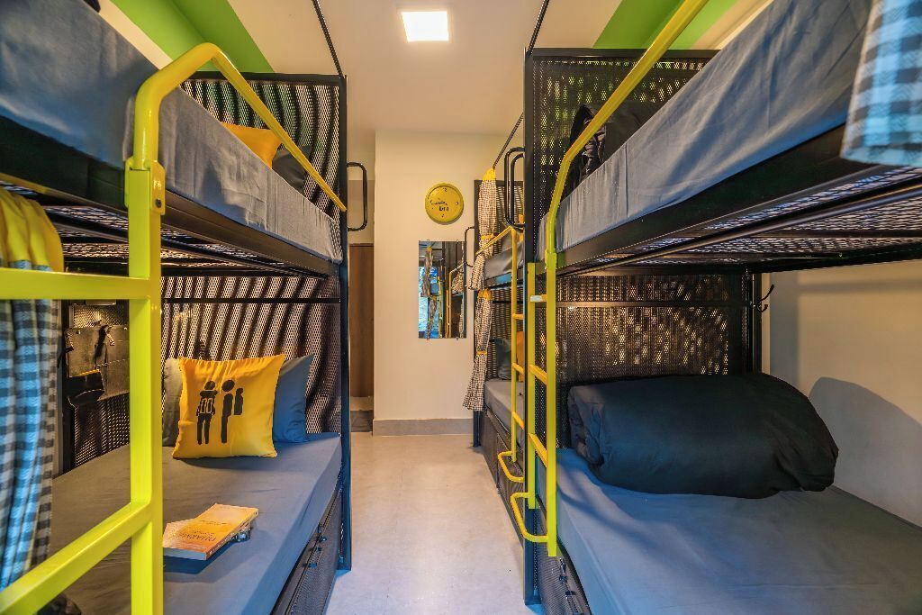 A dormitory room with bunk beds, a ladder, and a small table with a book.