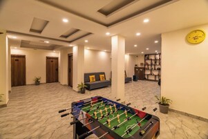 A spacious room with a foosball table, a sofa, and a clock on the wall.
