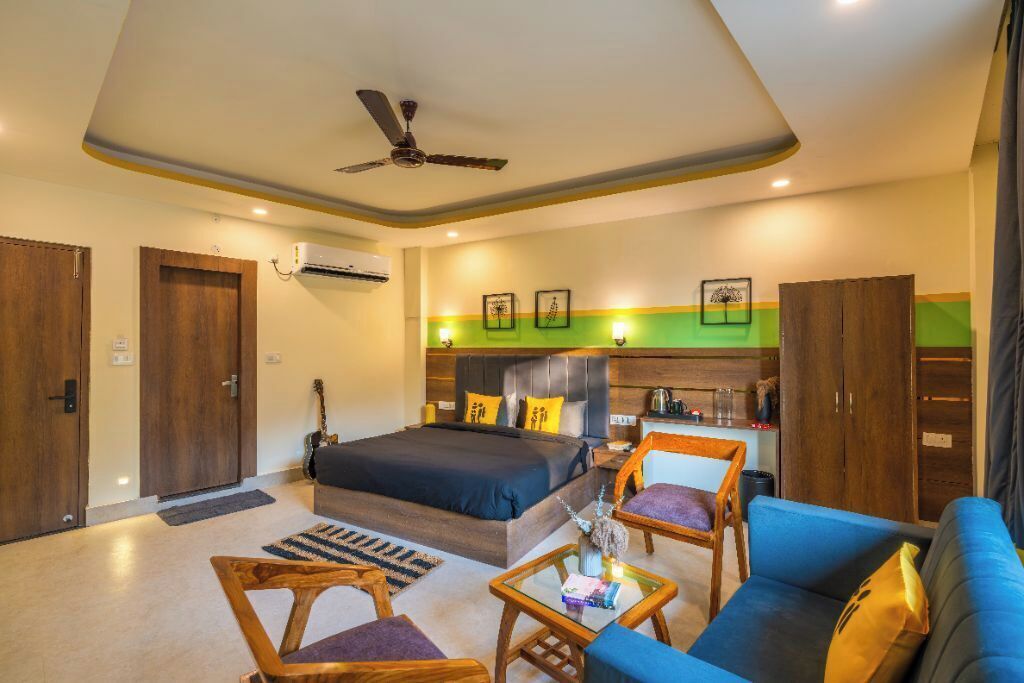 Une chambre d’hôtel comprenant un lit, un canapé, une chaise, une petite table, un ventilateur de plafond et un coin cuisine.
