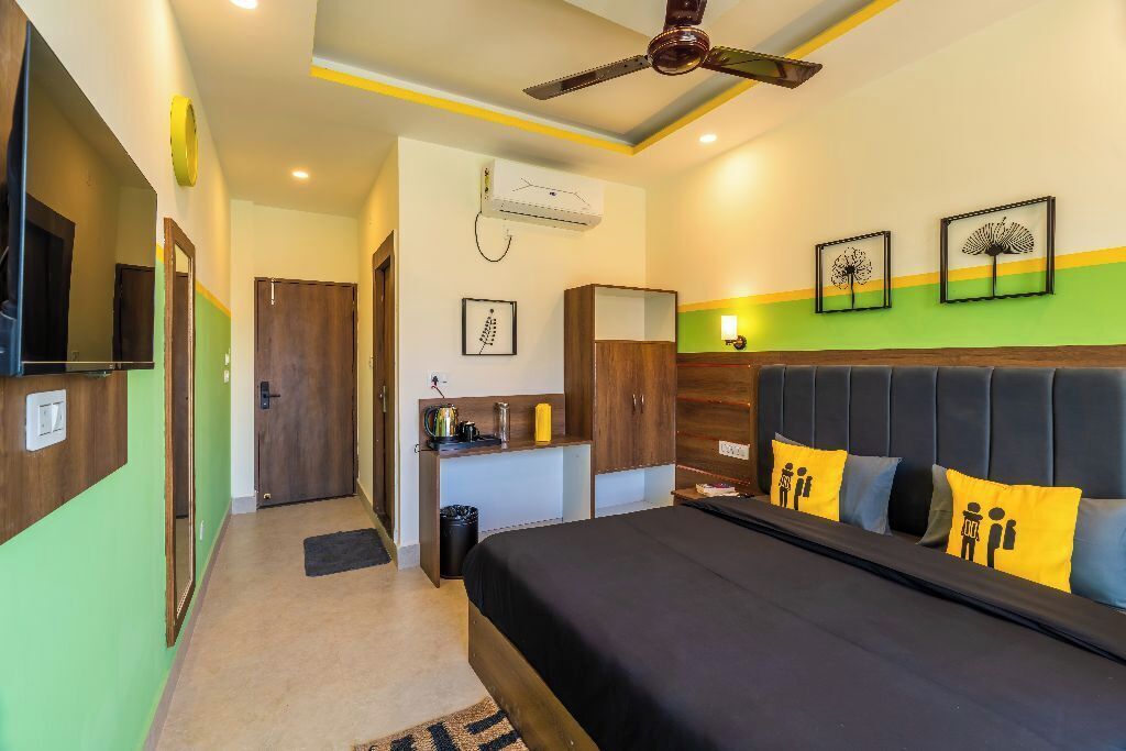 Une chambre d’hôtel équipée d’un lit, d’un bureau, d’un climatiseur et d’un ventilateur de plafond.
