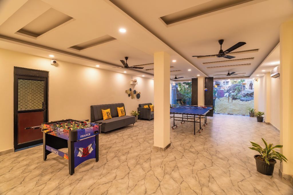 A spacious indoor area with a foosball table, a ping pong table, and a sofa with cushions.