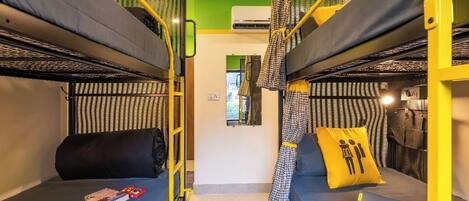 Camera con letto a castello, parete verde, una piccola finestra e cuscino giallo.