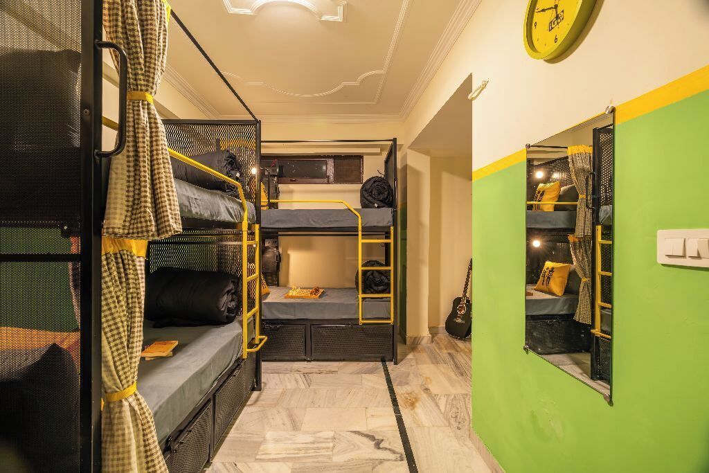 Une petite chambre avec des lits superposés, un petit bureau et un miroir.