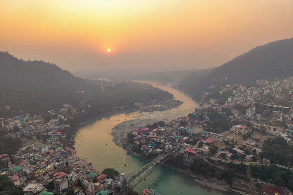 A river flowing through a town with a bridge and buildings along the riverbanks.