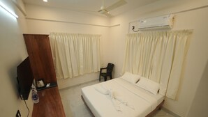 A hotel room with a bed, a wooden cabinet, a television, and an air conditioning unit. - Vallimony Luxury Stays-Padmanabha Temple (Thiruvananthapuram)