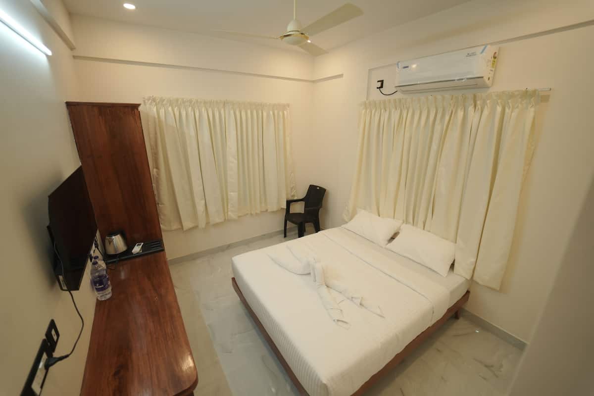 A hotel room with a bed, a wooden cabinet, a television, and an air conditioning unit.